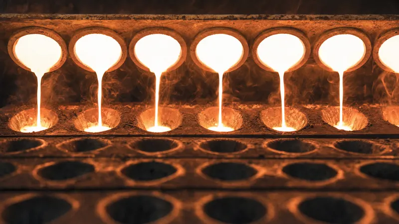 Fire assay crucibles pouring molten charge into a row of moulds